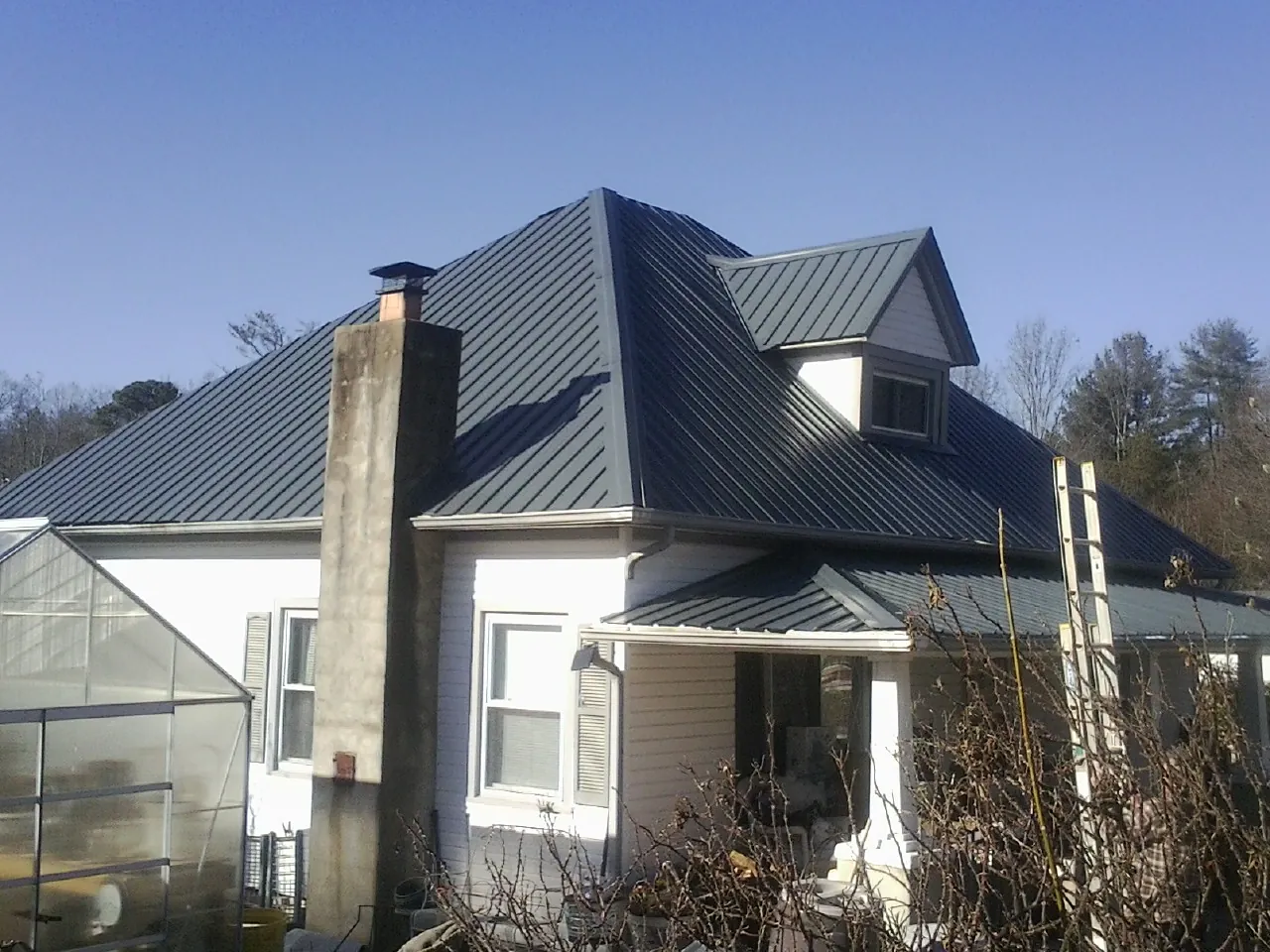 Dark blue standing seam metal roof on a white farmhouse with dormer — Slate & Tile Roof Repair by Roofing Brothers in Plain Dealing