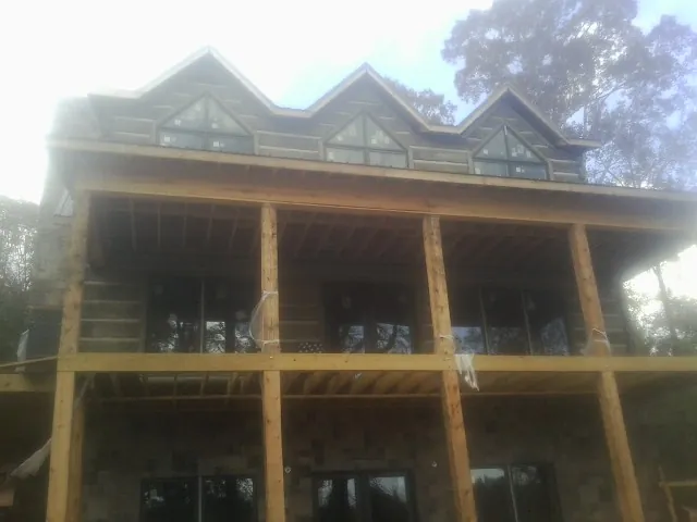 Dormers and porch framing on a large log home under construction — Roof Coating work by our crew in Plain Dealing