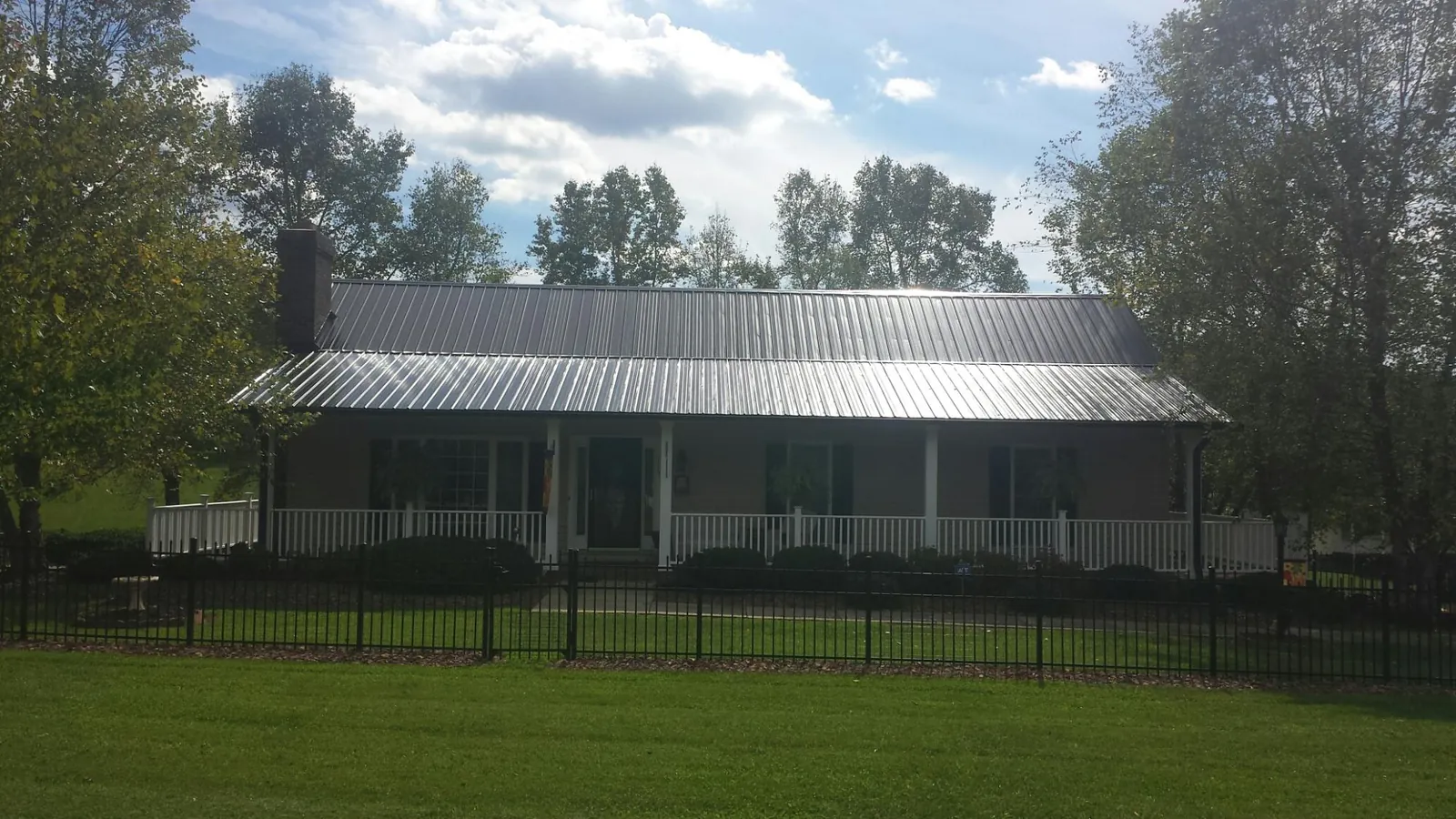 Gray metal roof on a brick ranch with a full width front porch — Gutter Guard Installation work by our crew in Plain Dealing