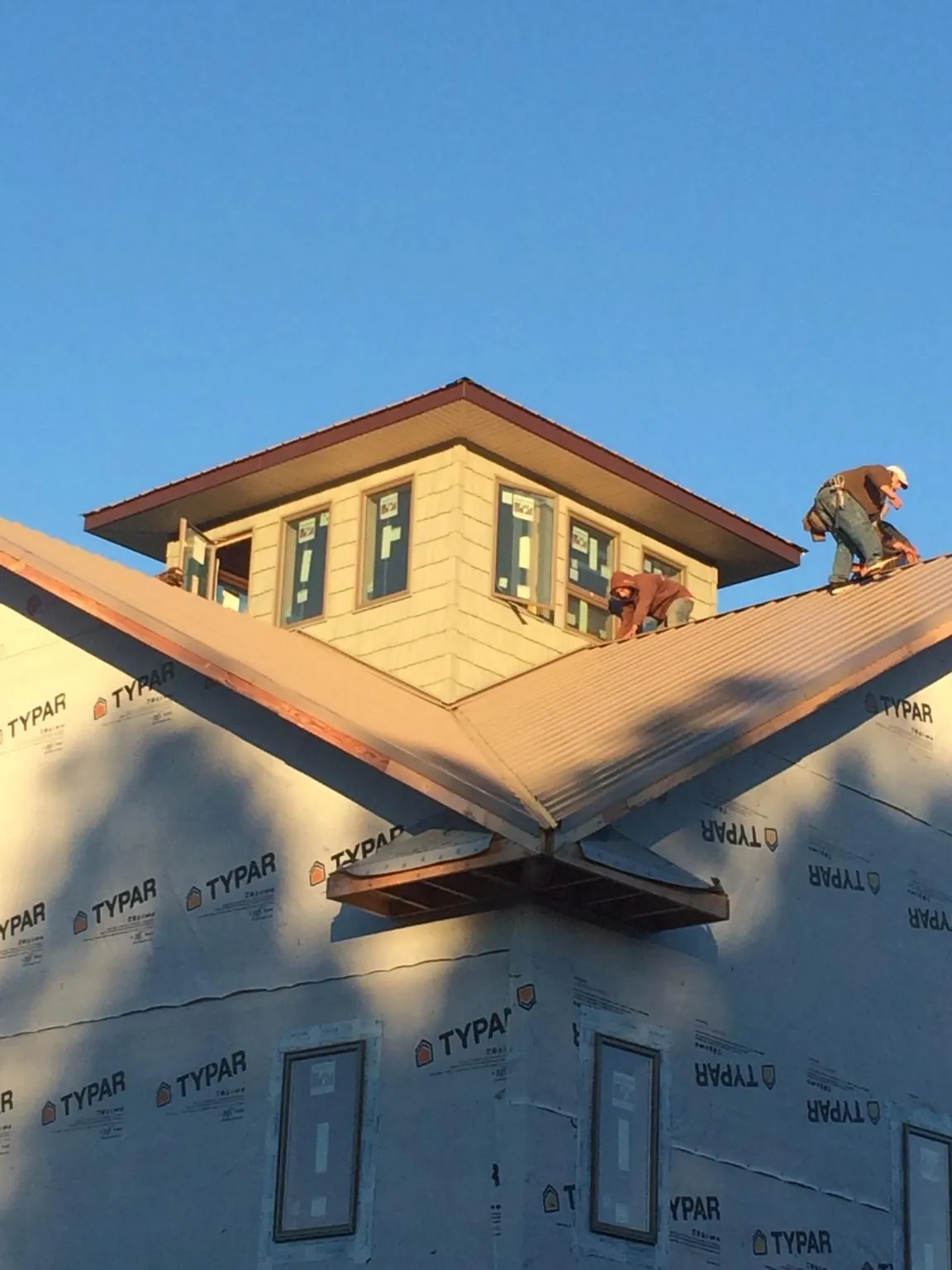 Roofers working around a rooftop cupola on a new metal roof at sunset — Roof Waterproofing in Plain Dealing by Roofing Brothers